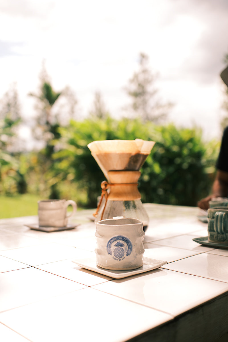 Chemex coffee maker with a mug on a table outdoors. Top-quality single estate coffee beans displayed with holiday lights, elegantly packed for birthdays or Christmas – a best-selling coffee gift idea for coffee lovers.