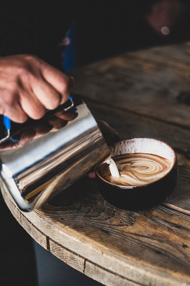 Person pouring coffee into a cup with a wooden surface and dark background. Organic coffee beans, father day gift for father, birthday gift trends, best coffee beans, best gift ideas, purist coffee, fresh coffee beans, gift for coffee lovers, best coffee beans top selling coffee beans, coffee lovers, coffee gift ideas, single estate, mother day gift 2026, birthday gift 2025, Jamaica Blue Mountain coffee, great birthday gift, best coffee gift, mother day gift for mom, top quality coffee, fresh coffee beans,
